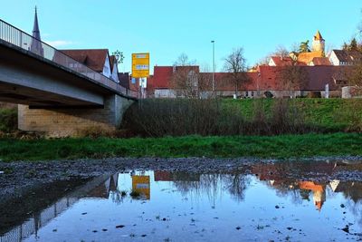 Arch bridge over river by buildings against sky