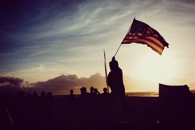 Silhouette people at beach against sky during sunset