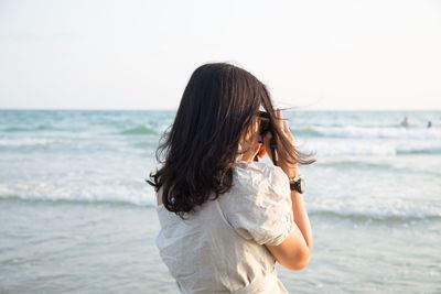 Woman standing at beach against sky