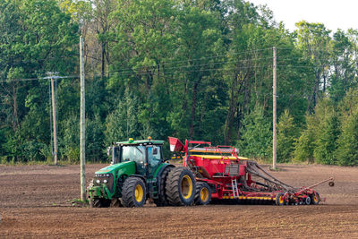 Tractor on field against trees in forest