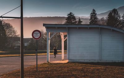 Road sign by building against sky