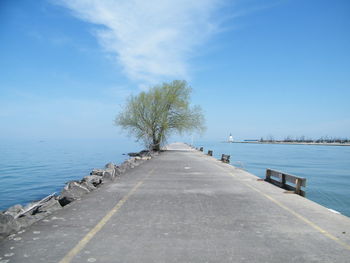 Empty road by sea against blue sky