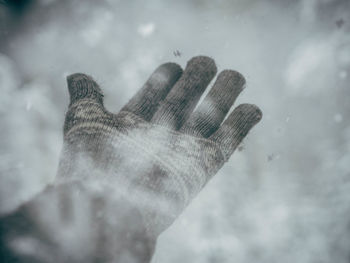 Close-up of gloved hand against snow