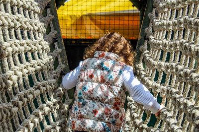 Rear view of girl on jungle gym at playground