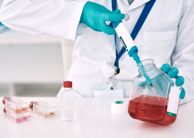 Midsection of scientist holding chemical in laboratory