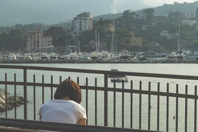 Woman sitting on beach against sea in city