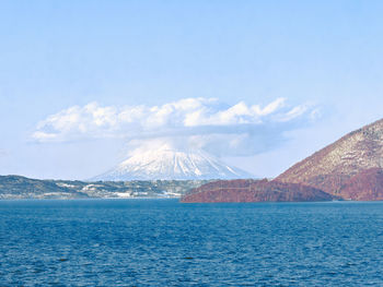 Scenic view of lake against cloudy sky with mountain as background 