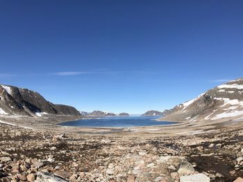 Scenic view of sea and mountains against blue sky