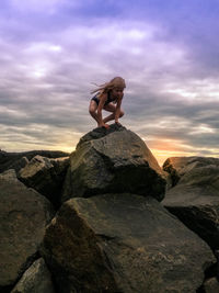 Full length of girl on rock against sky during sunset