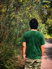 Rear view of man standing by tree in forest