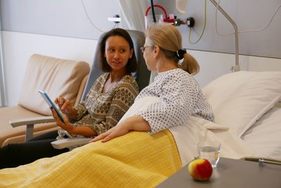 Grandmother and granddaughter using digital tablet in hospital ward