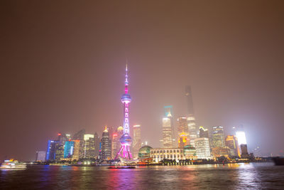 Oriental pearl tower by huangpu river in city at night