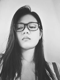 Low angle view of beautiful woman wearing eyeglasses against white wall