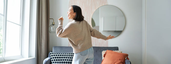 Side view of young woman sitting on sofa at home