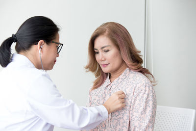 Close-up of doctor examining patient against wall