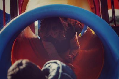 Low angle view of woman sliding in slide at playground