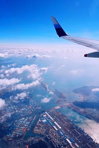 Aerial view of aircraft wing over cityscape against sky