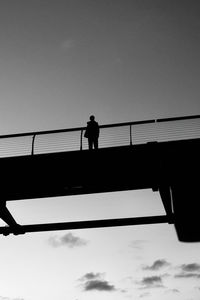 Low angle view of people walking on bridge against clear sky