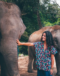 Woman touching elephant while standing in zoo