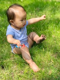 High angle view of baby girl sitting on grassy field