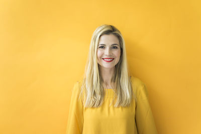 Portrait of a smiling young woman against yellow background