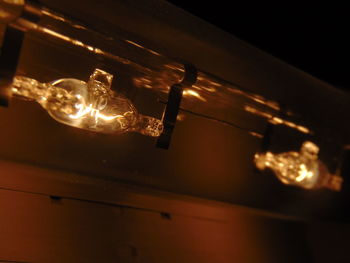 Low angle view of illuminated light bulb hanging at night