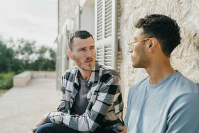 Male friends talking while sitting at backyard