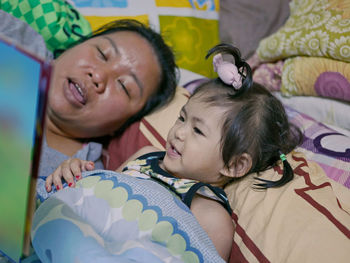 A baby girl, 2 years old, enjoys listening to her auntie reading aloud to her a bedtime story