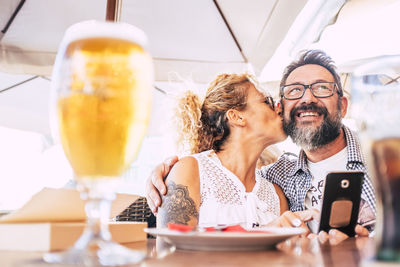 Woman kissing man while having food at table