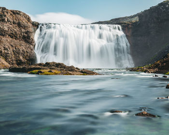 Scenic view of waterfall against sky