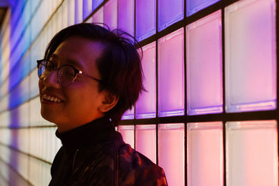 Young man standing against illuminated wall