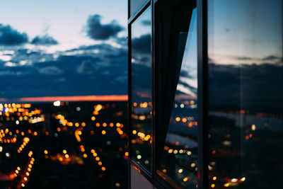 Reflection of illuminated city seen on window at dusk