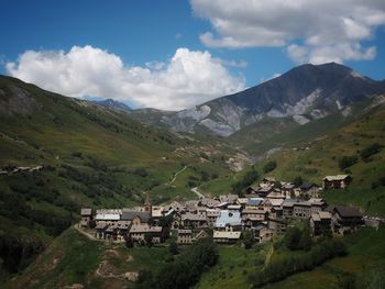 Houses on field by mountains against sky