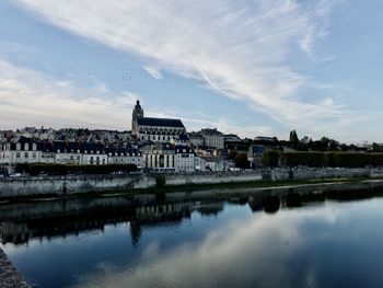 View of buildings by river against sky in city