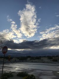 Road sign on street in city against sky