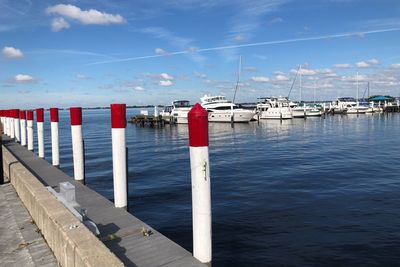 Wooden posts in sea against sky