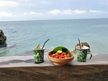 Food on table by sea against sky