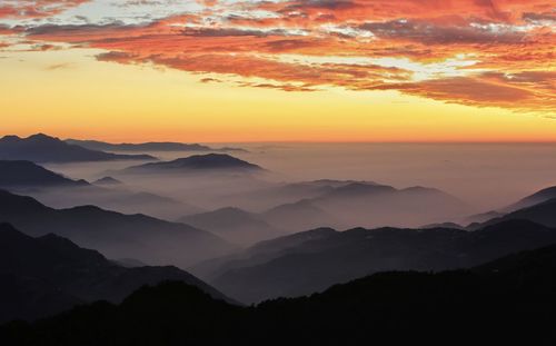 Scenic view of silhouette mountains against orange sky