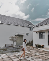 Woman standing by building against sky