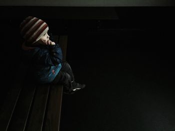 High angle view of baby boy sitting on bench in darkroom