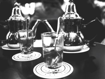 Spoons in drinking glass on table by jars