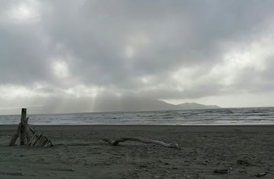 Scenic view of beach against cloudy sky