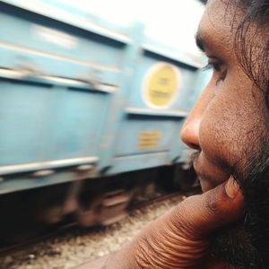 Cropped image of thoughtful bearded man looking at train