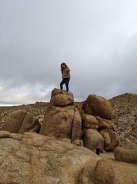 Rear view of man standing on rock against sky