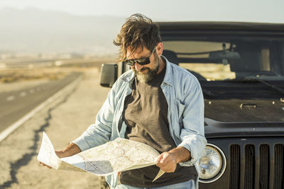 Man wearing sunglasses while standing by car