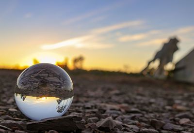 Close-up of crystal ball on field during sunset