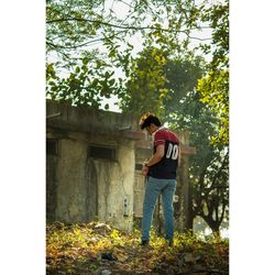 Side view of young man standing against plants