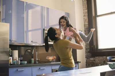 Mother lifting daughter in kitchen