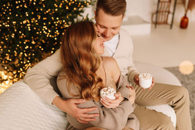 A couple in love hugging and relaxing on a christmas holiday in the decorated interior of the house