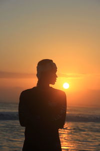 Silhouette man standing against sea during sunset